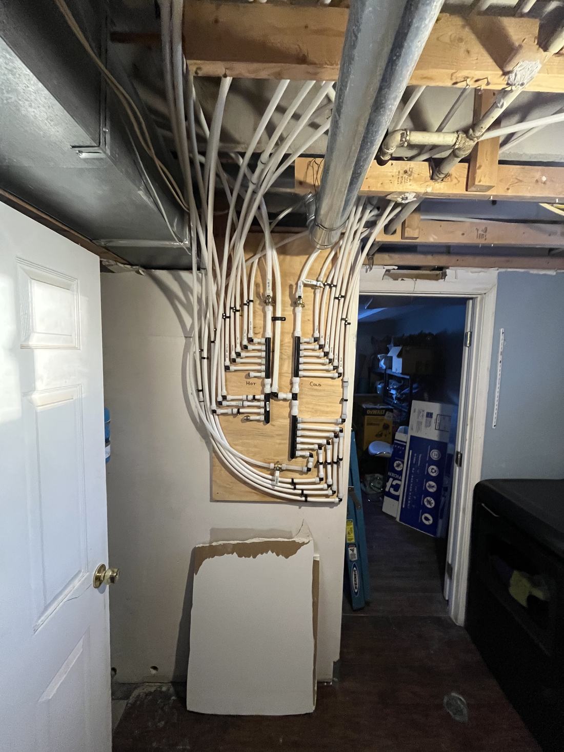 New PEX water manifold with labelled hot and cold lines in a basement
