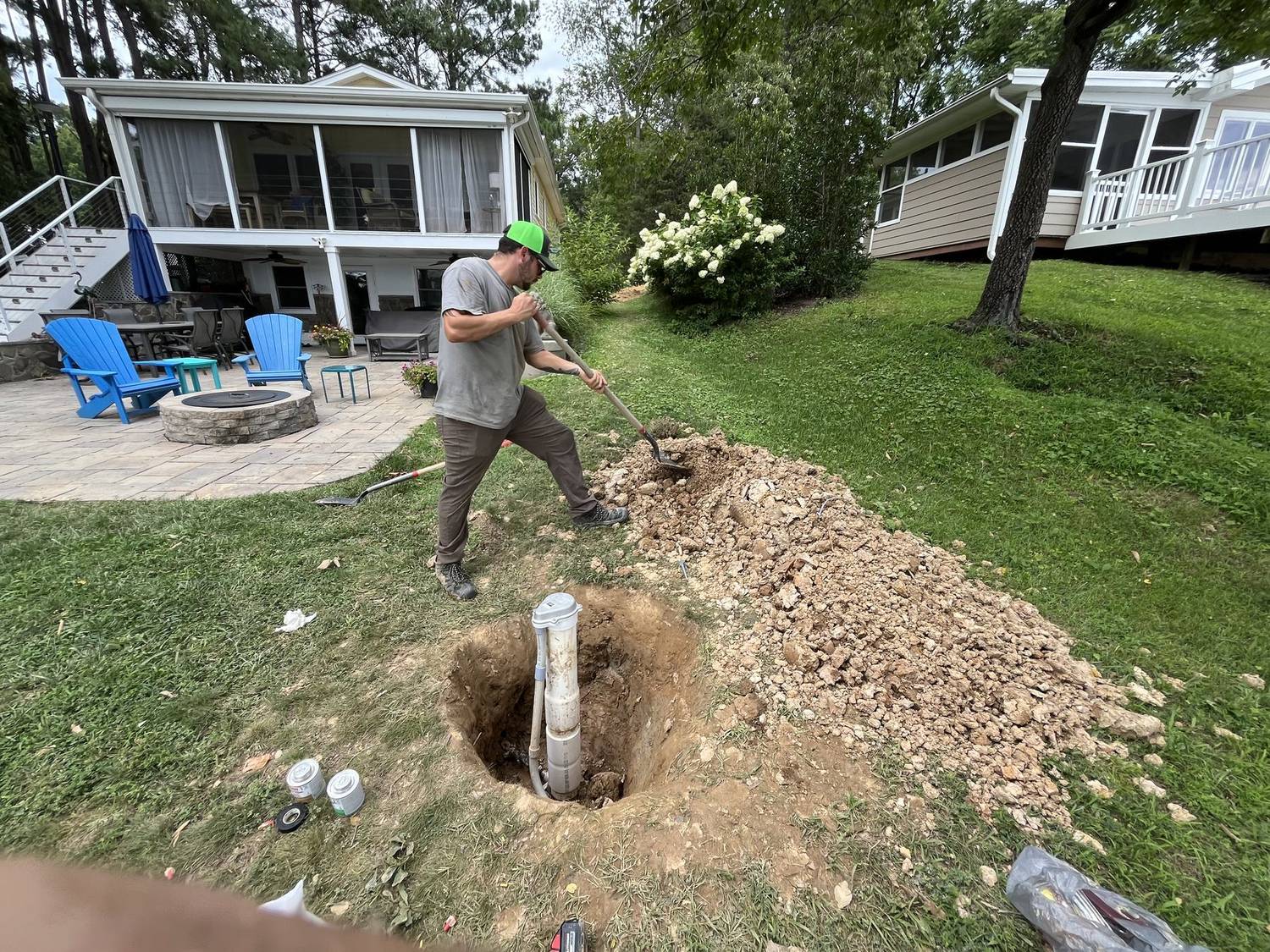 RJ technician digging to reach a sewer cleanout in a backyard